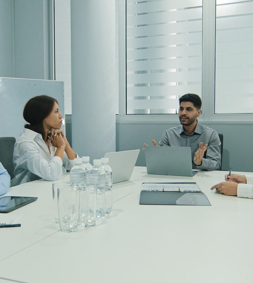 young-indian-team-leader-sitting-with-colleagues-2022-12-01-06-12-18-utc.jpg